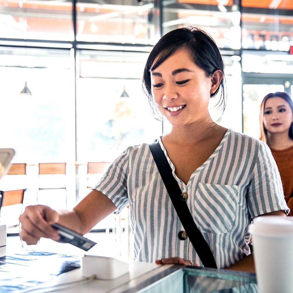 Young woman using credit card reader at coffee shop counter