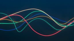 Blue, green, red, brown and white wire in wave pattern on dark blue background - stock photo