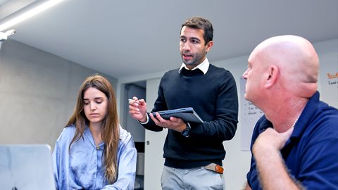 A facilitator explains new processes to a manager and frontline operator