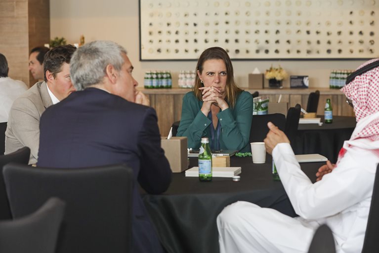 Summit attendees sitting around a table in conversation.