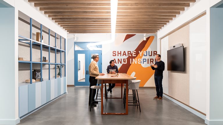 Three colleagues in discussion around a common table in the office